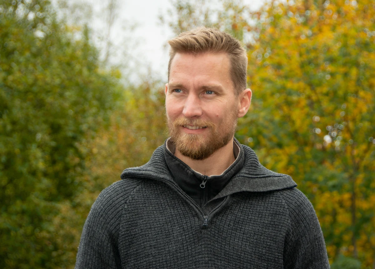 Tellef T. Christensen utendørs foran trær i høstfarger
